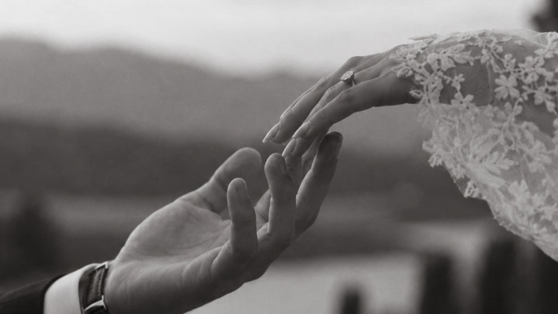Two hands reaching for one another, one wearing a lace glove