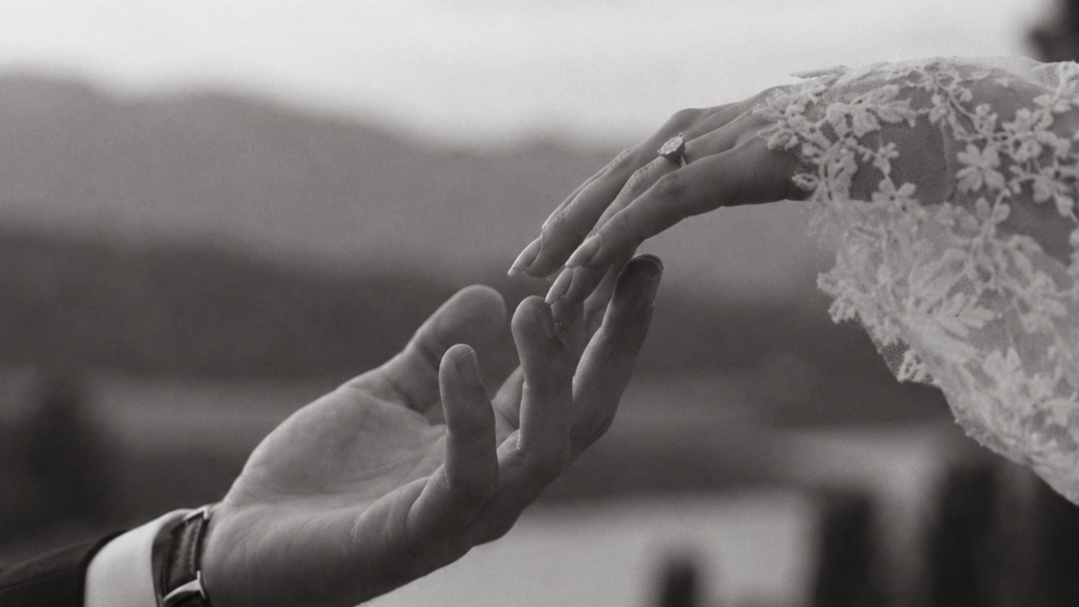 Two hands reaching for one another, one wearing a lace glove
